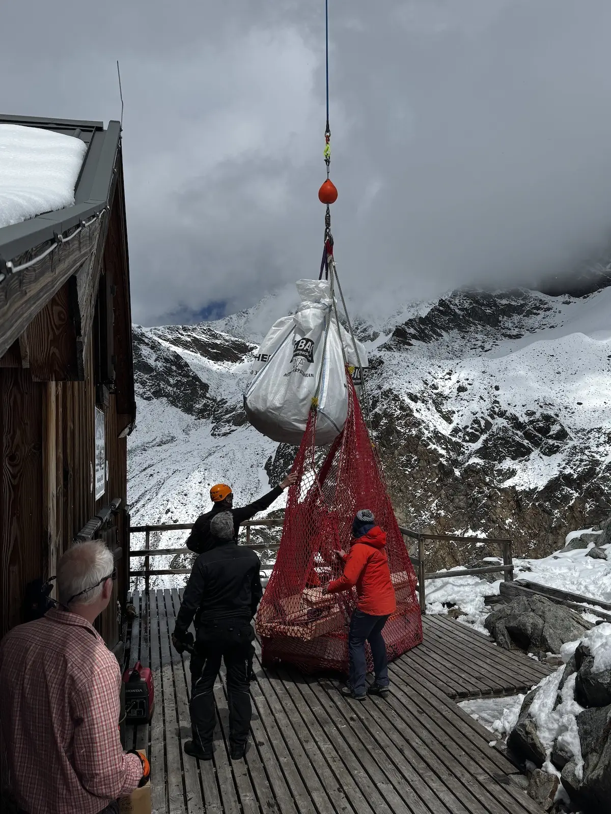 Ein Helikopter Pilot lädt Holz direkt vor der Tür der Rauhekopfhütte ab. | © Helmut Schgeiner